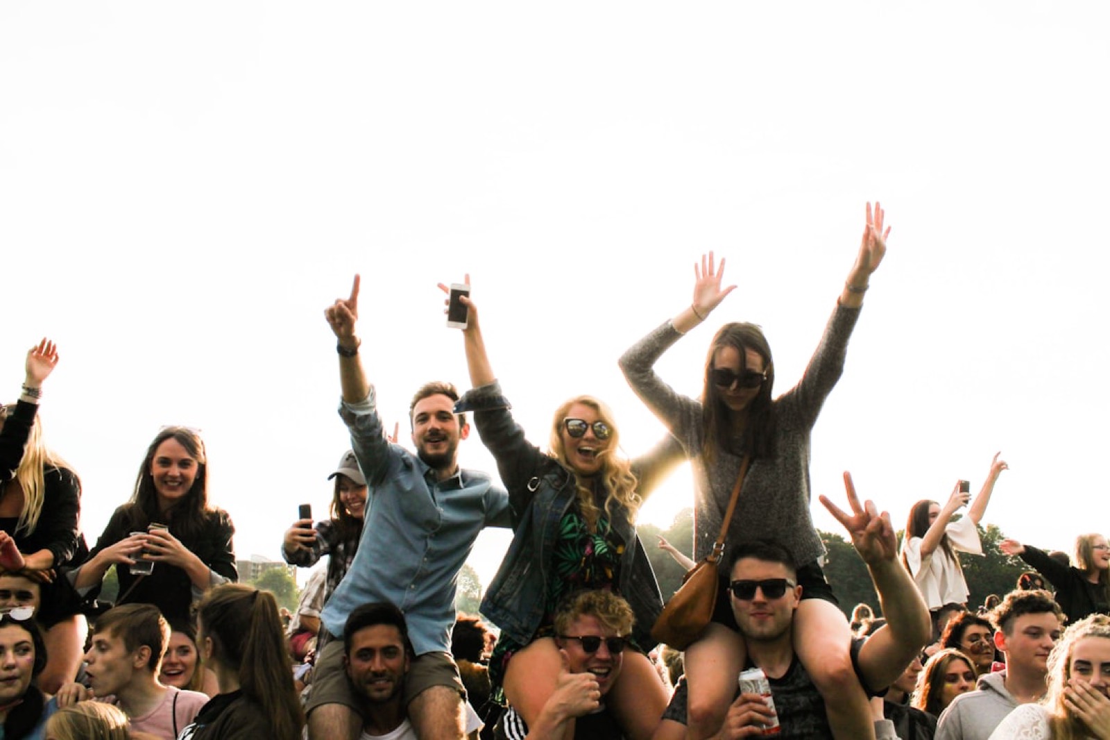 Public d'un festival en plein air levant les bras devant la scène
